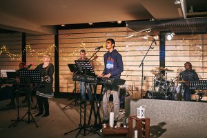 Five musicians of different nationalities perform on stage with string lights